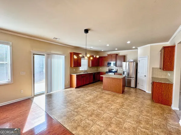 a kitchen with stainless steel appliances kitchen island granite countertop a refrigerator and a stove top oven