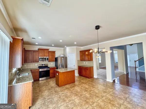 a open kitchen with stainless steel appliances kitchen island granite countertop a refrigerator a stove top oven and a sink