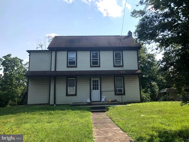 a view of a house with a yard plants and large tree