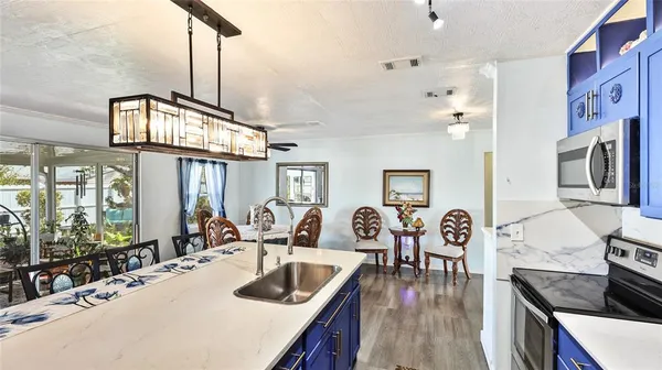 a kitchen with granite countertop a stove a sink a dining table and chairs with wooden floor