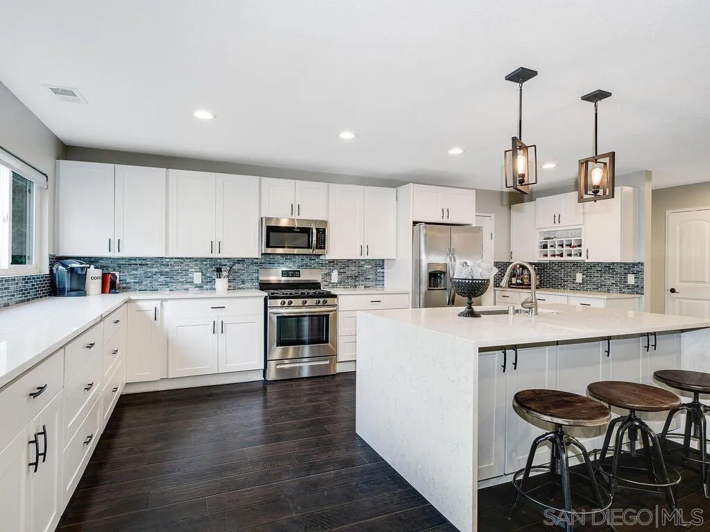 4427 68th Street La Mesa, CA 91942 - Photo 1 of 33 a kitchen with white cabinets stainless steel appliances and wooden floor