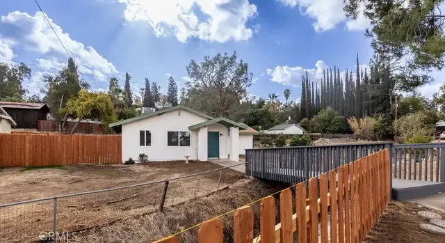 a view of a house with wooden fence next to a yard