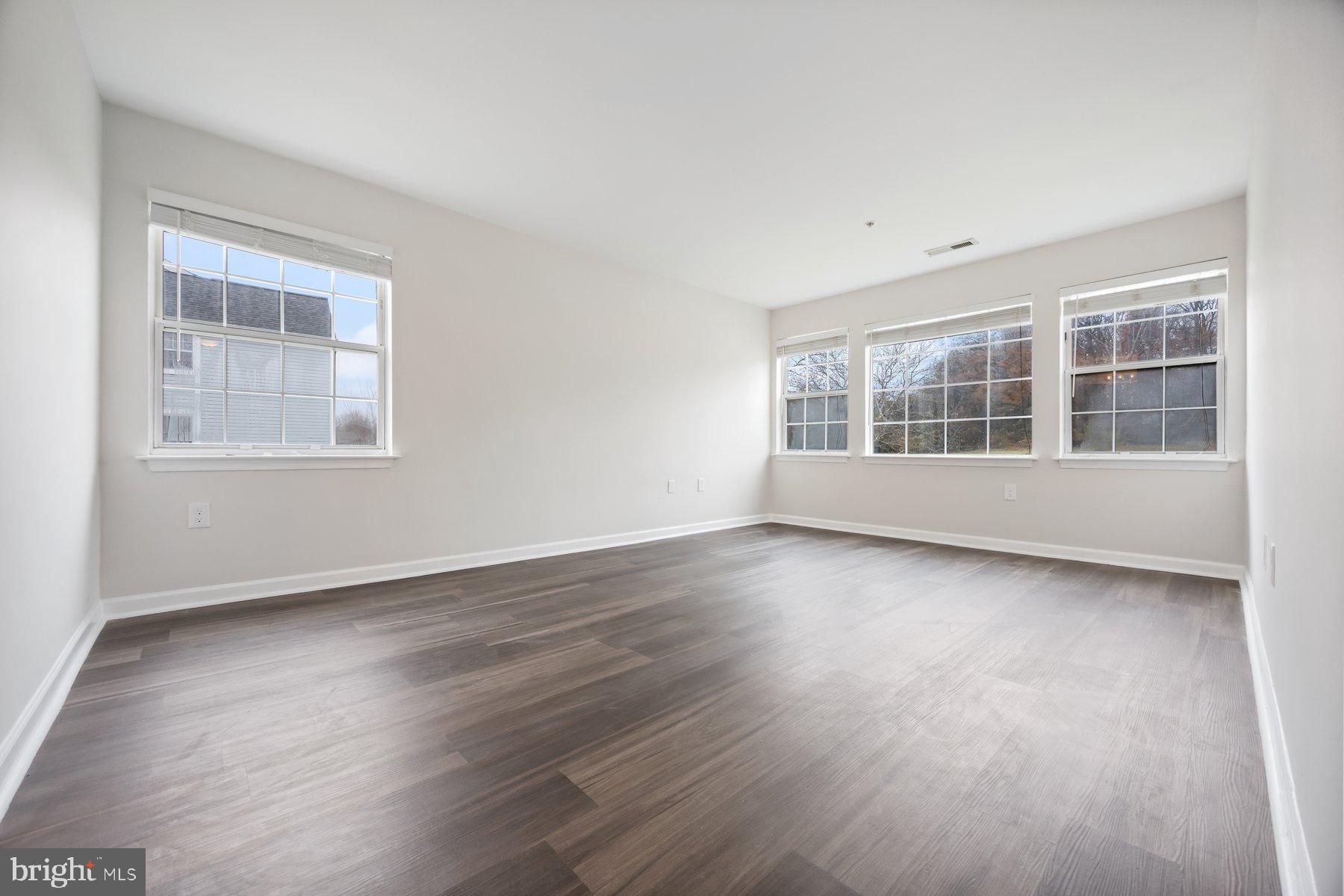 8393 Montgomery Run Road, Unit H Ellicott City, MD 21043 - Photo 19 of 30 an empty room with wooden floor and windows