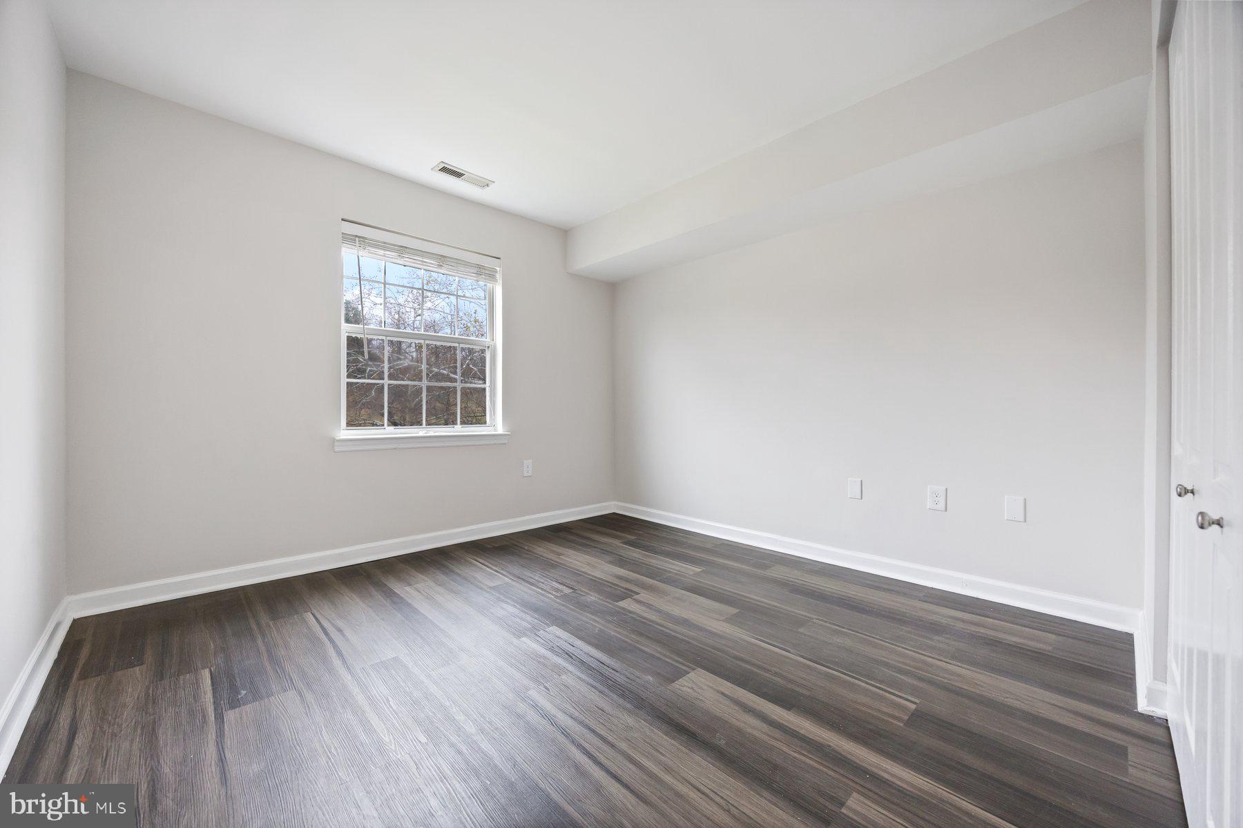 8393 Montgomery Run Road, Unit H Ellicott City, MD 21043 - Photo 26 of 30 an empty room with wooden floor and windows