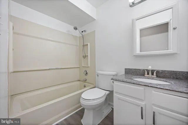 a bathroom with a granite countertop toilet sink and mirror