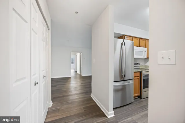 a view of a kitchen with refrigerator and wooden floor