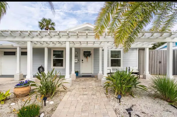a view of a house with potted plants and a table and chair
