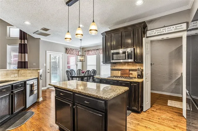 a kitchen with a center island wooden floor and a refrigerator