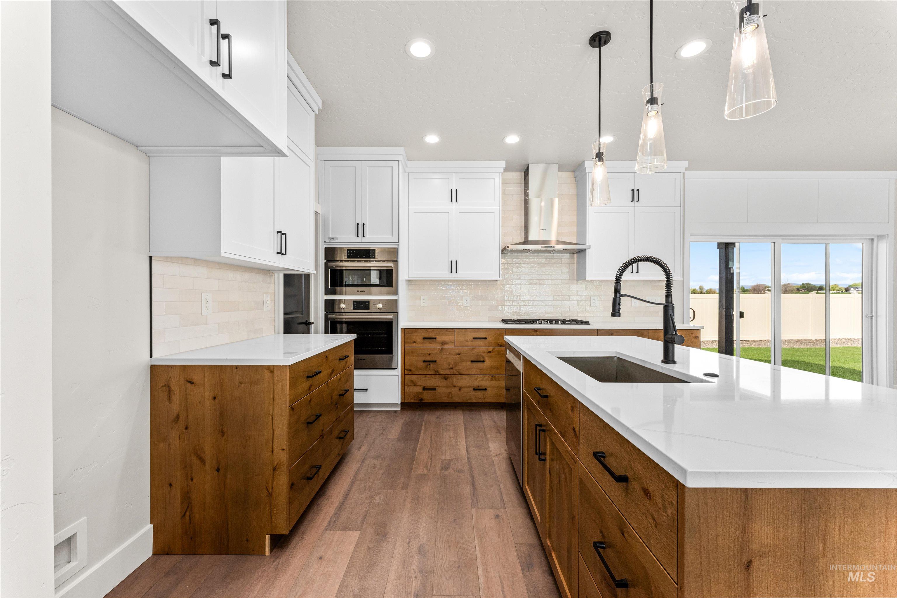 2709 West Gidran Meridian, ID 83642 - Photo 16 of 43 Spacious kitchen featuring an expansive island with a built-in sink, white countertops, wood-finish cabinetry, and stainless steel appliances