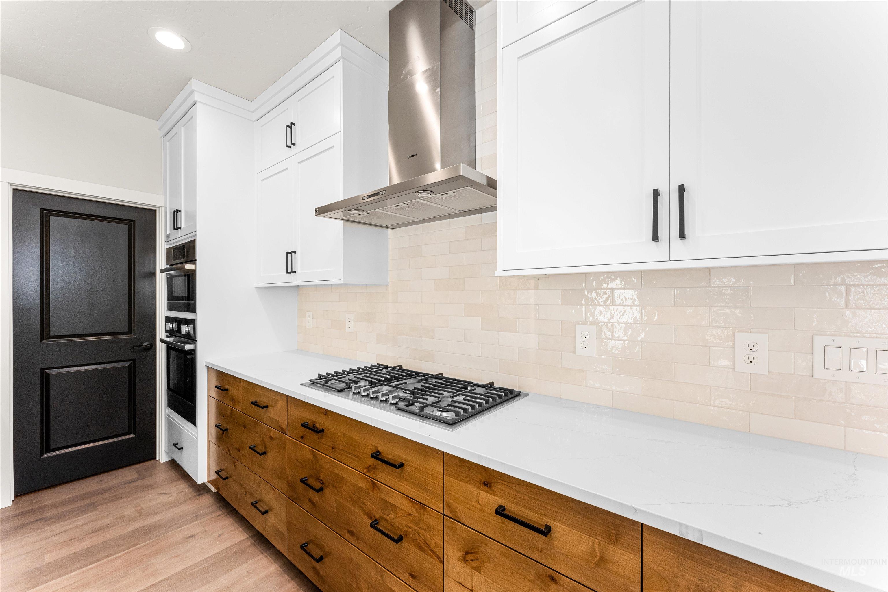 2709 West Gidran Meridian, ID 83642 - Photo 17 of 43 Modern kitchen featuring two-tone cabinetry with white upper cabinets and wood-finish lower drawers, complemented by a white countertop