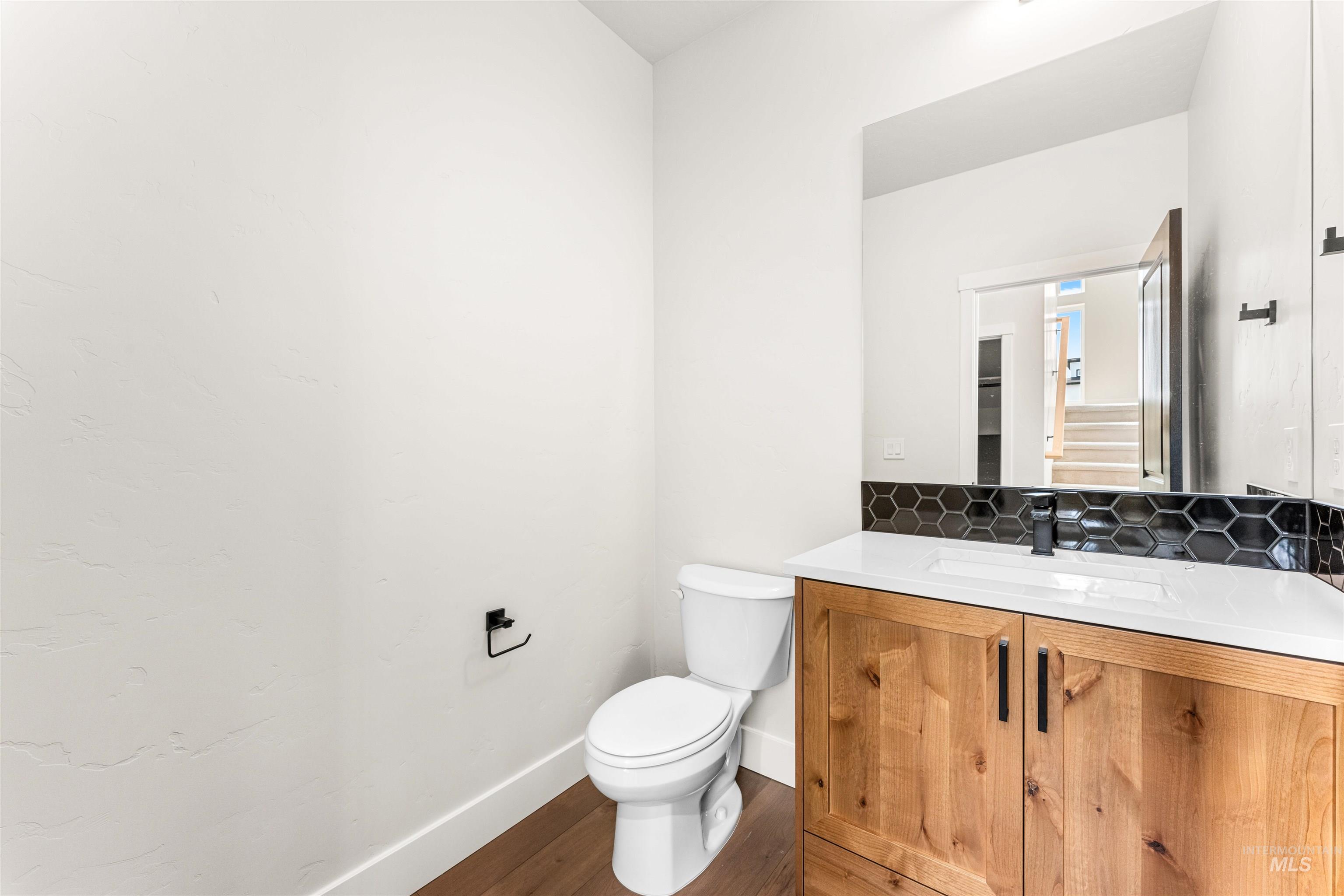 2709 West Gidran Meridian, ID 83642 - Photo 18 of 43 Powder room featuring a single-sink vanity with wood-finish cabinetry, a white countertop, and a black hexagonal tile backsplash