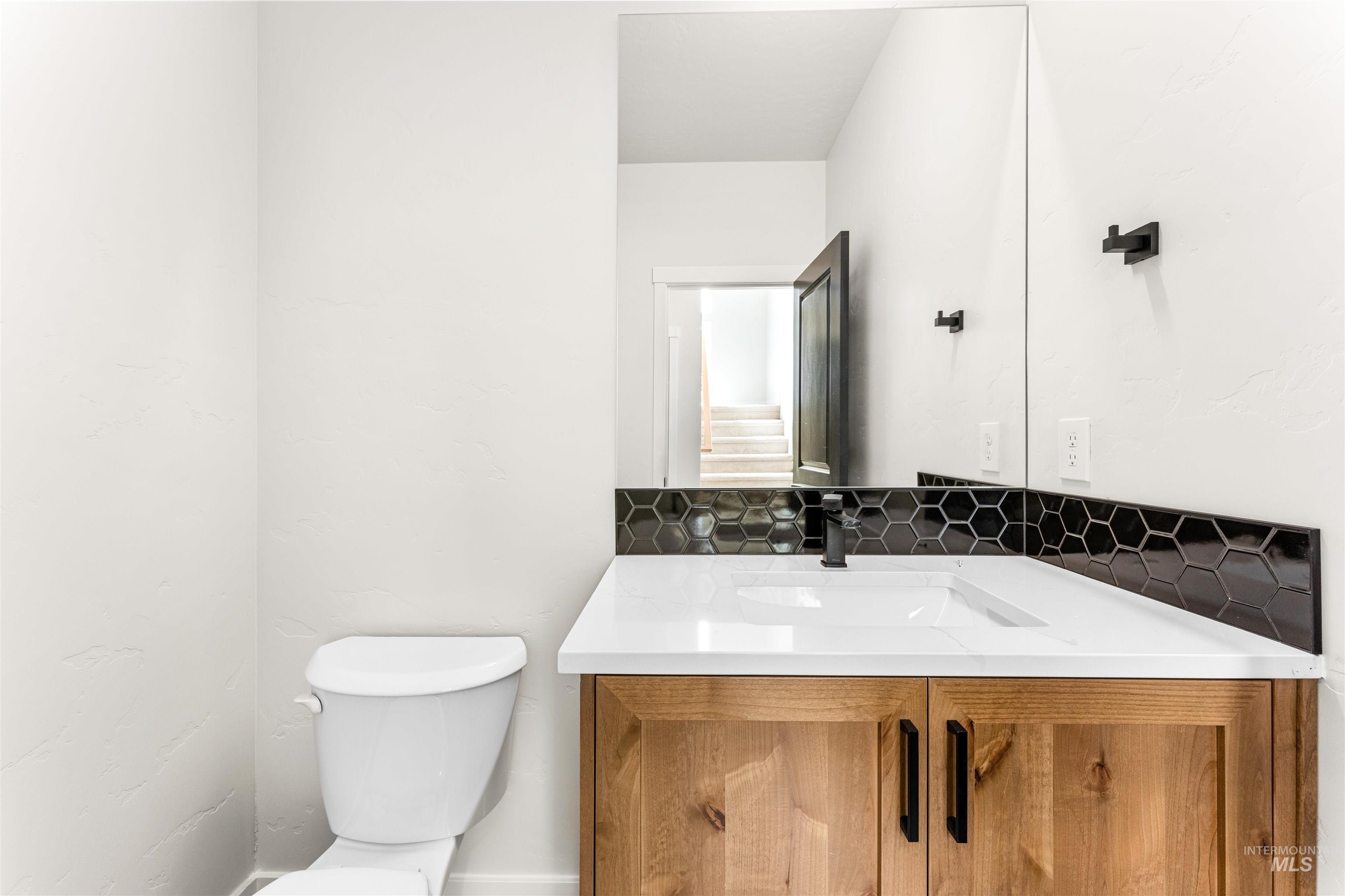 2709 West Gidran Meridian, ID 83642 - Photo 19 of 43 Modern vanity featuring a wood-finish cabinet with black hardware, white countertop, and integrated sink