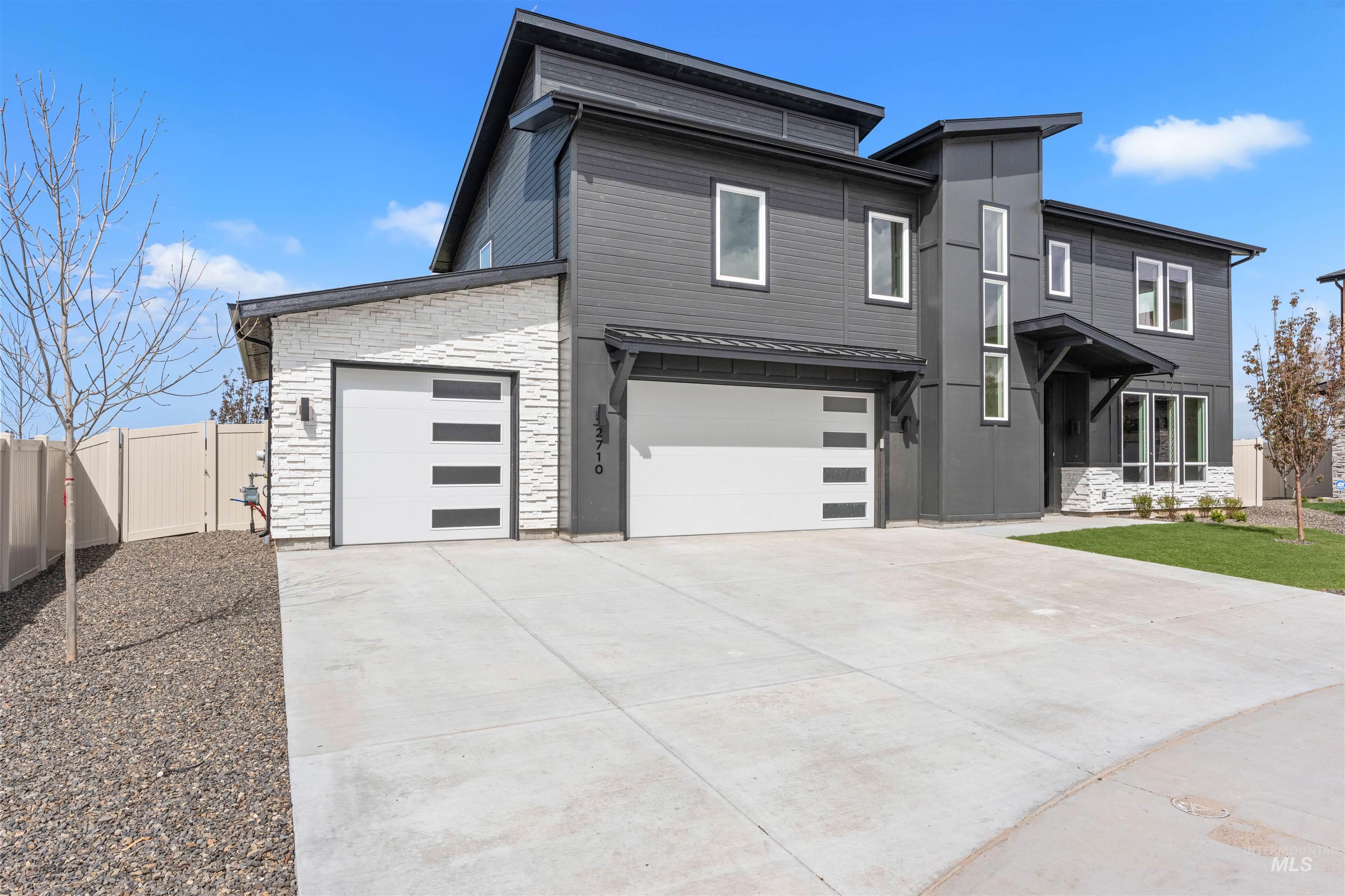 2709 West Gidran Meridian, ID 83642 - Photo 43 of 43 Modern two-story residence featuring a dark gray facade, stacked white stone accents, and two contemporary garage doors with horizontal window panels