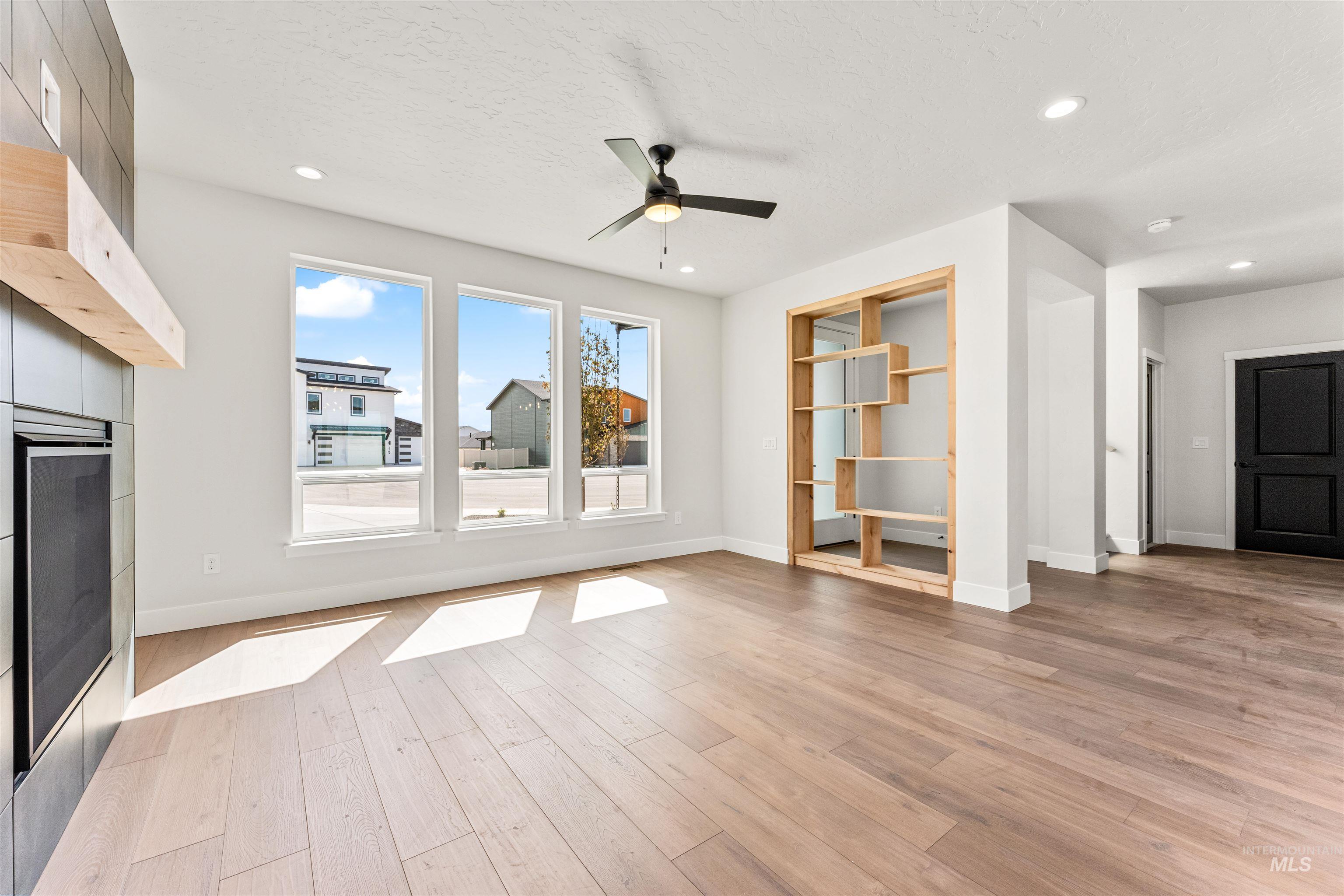 2709 West Gidran Meridian, ID 83642 - Photo 5 of 43 Expansive living area featuring light wood-finish flooring, a contemporary fireplace with a light wood mantel, and three large windows