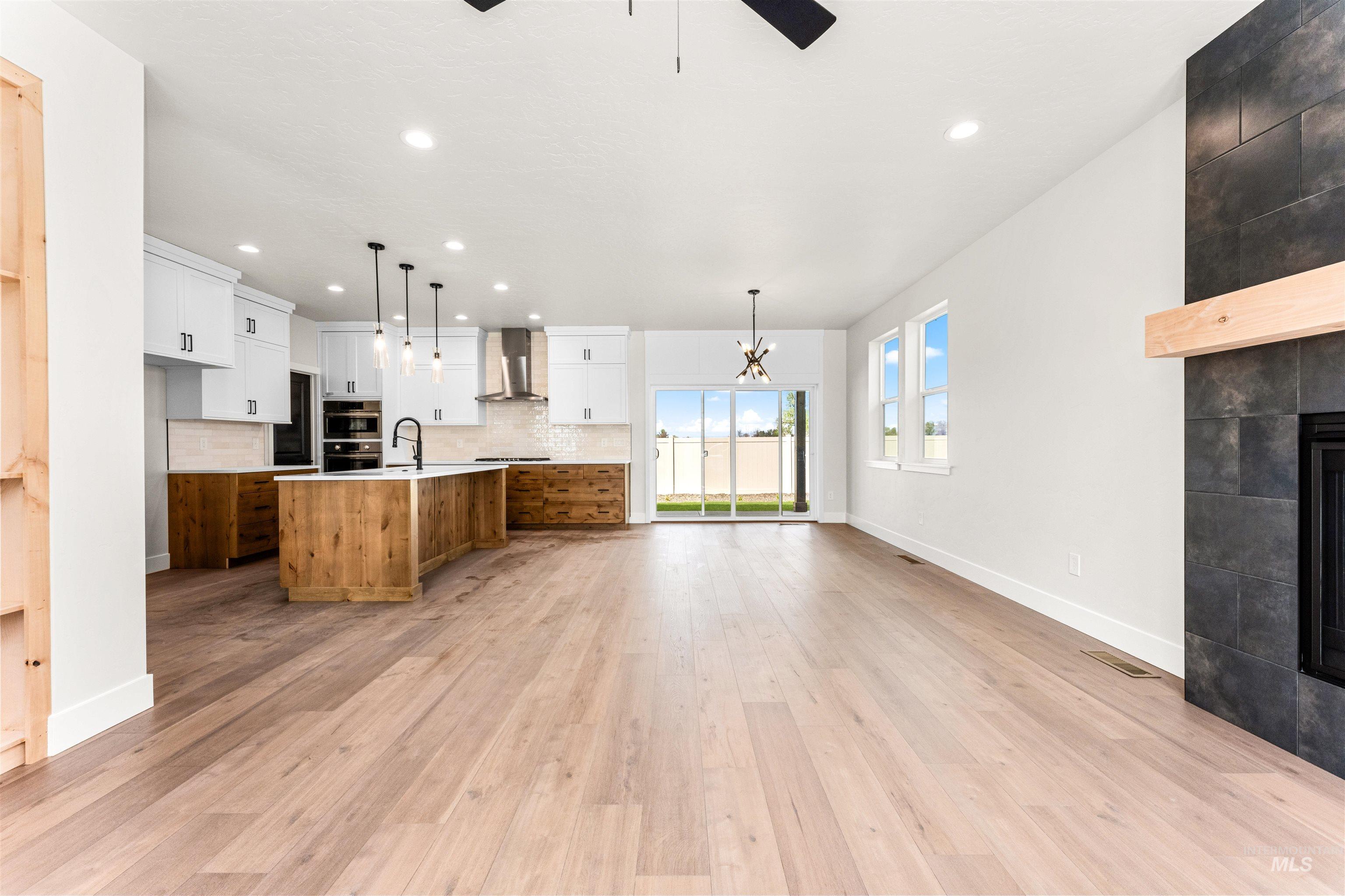 2709 West Gidran Meridian, ID 83642 - Photo 8 of 43 Open-concept living area featuring wood-finish flooring, a contemporary kitchen with a large island, stainless steel appliances, and a tile backsplash