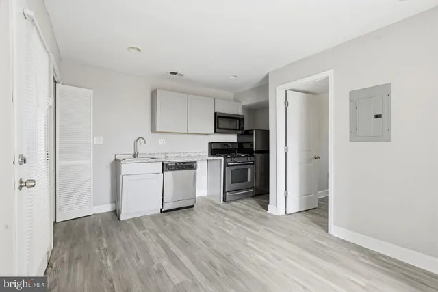 a kitchen with a refrigerator a stove top oven and wooden floor