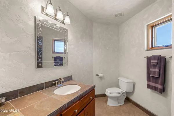 a bathroom with a granite countertop toilet sink and mirror
