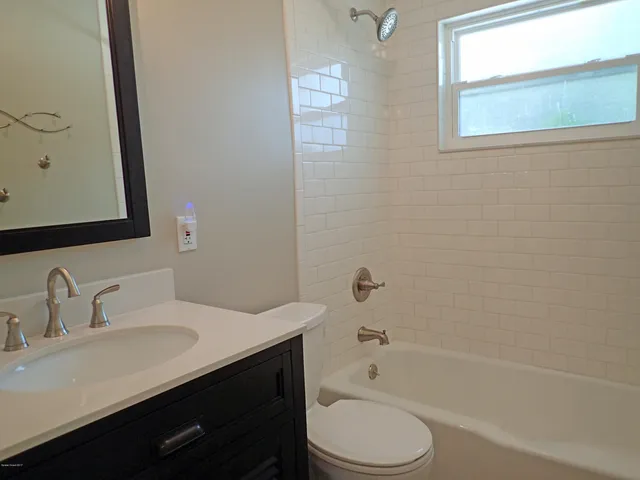 a bathroom with a bathtub sink vanity mirror and toilet