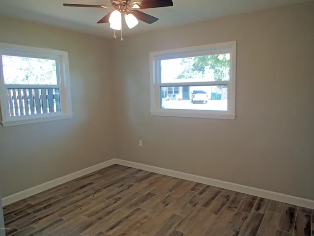 a view of an empty room with wooden floor and a window