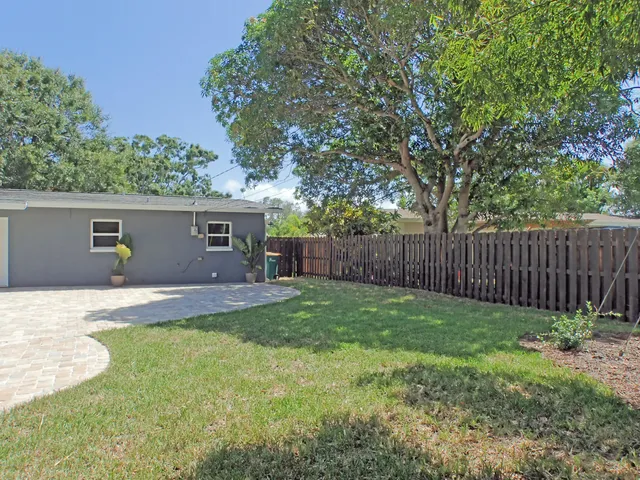 a view of a backyard with table and chairs and a large tree