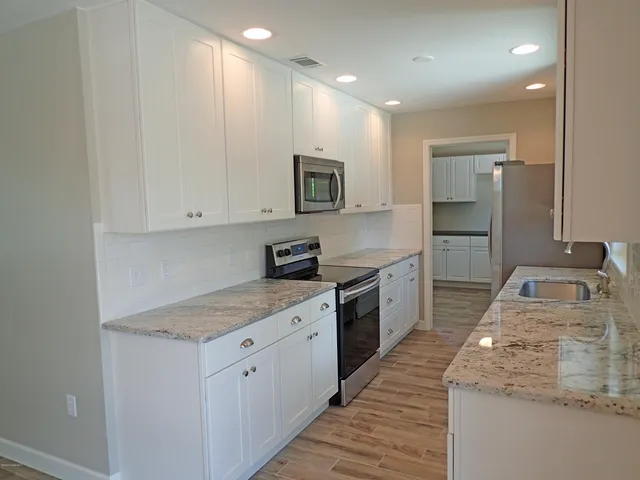 a kitchen with granite countertop sink stainless steel appliances and white cabinets