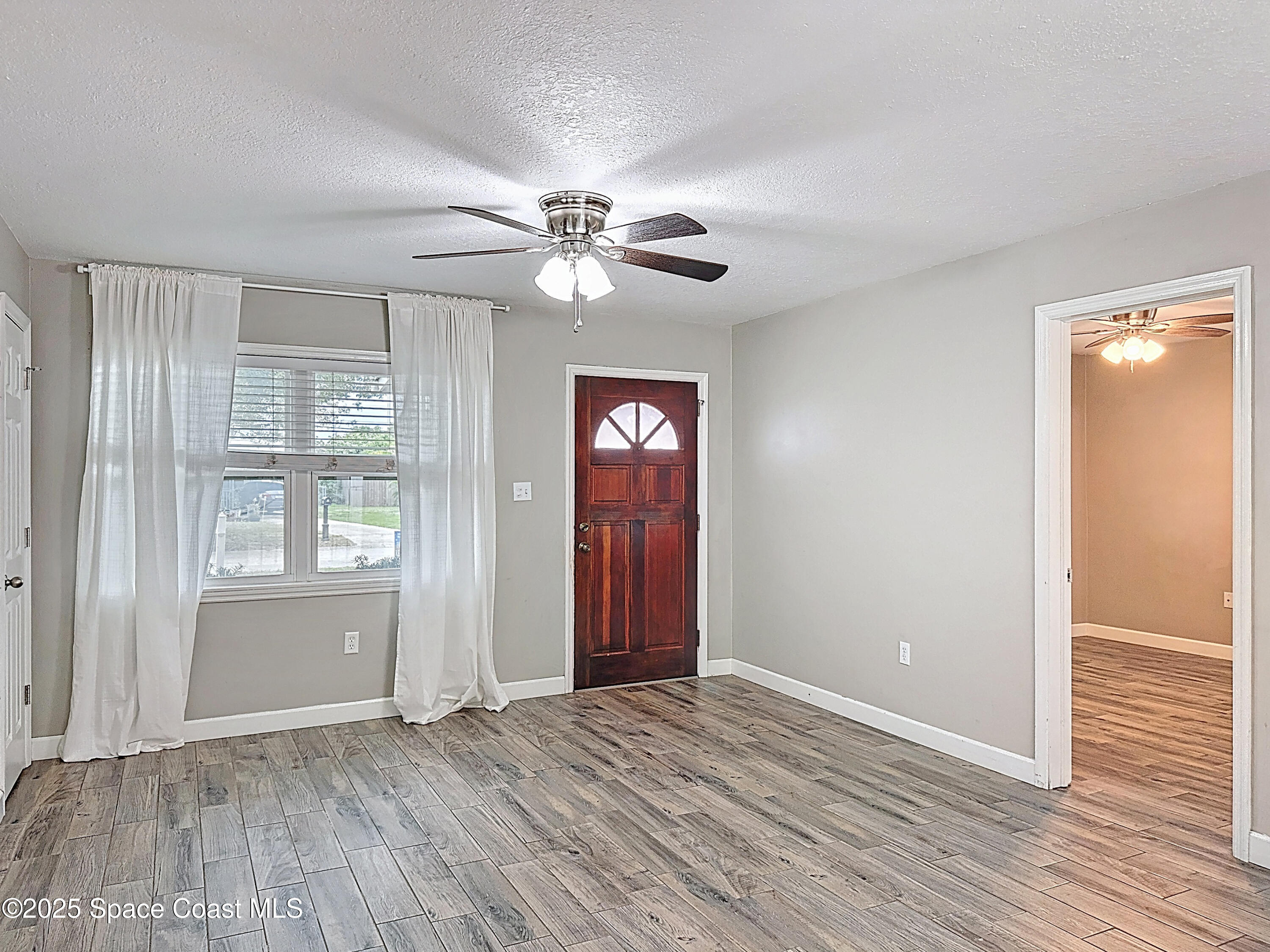 170 Moore Avenue Merritt Island, FL 32952 - Photo 6 of 23 an empty room with wooden floor chandelier fan and windows