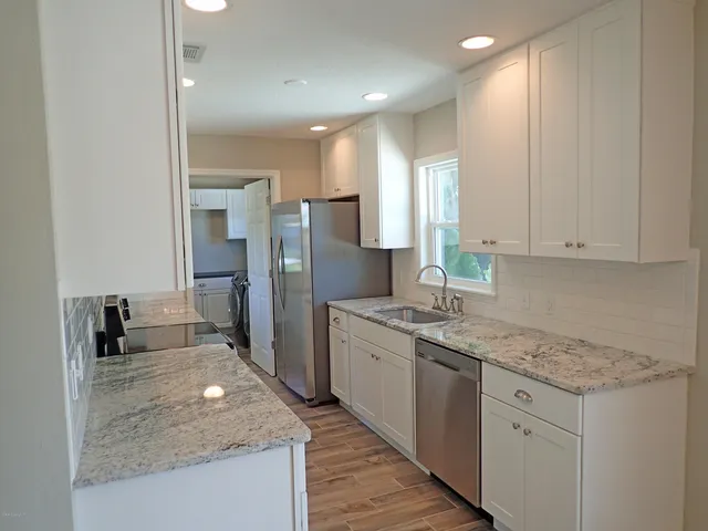 a kitchen with stainless steel appliances granite countertop a sink stove and refrigerator