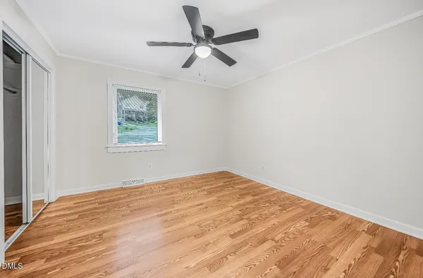 a view of empty room with wooden floor and ceiling fan