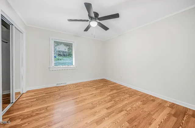 a view of empty room with wooden floor and ceiling fan