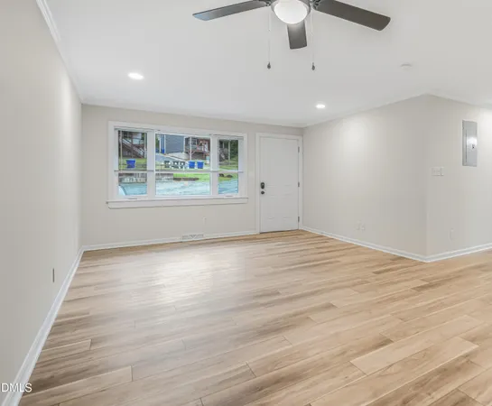 an empty room with wooden floor and windows