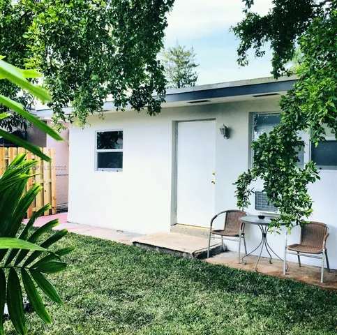 a backyard of a house with table and chairs potted plants