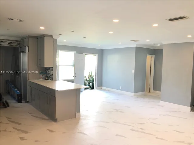 a large kitchen with kitchen island granite countertop a sink and a refrigerator