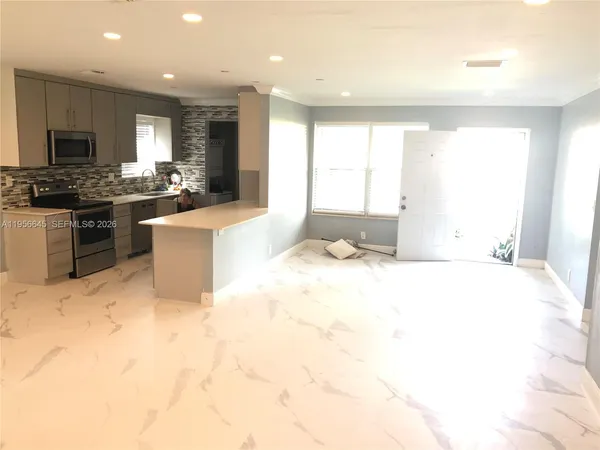 a large kitchen with kitchen island granite countertop a stove a sink a refrigerator white cabinets and wooden floor