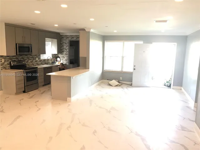 a large kitchen with kitchen island granite countertop a stove a sink a refrigerator white cabinets and wooden floor