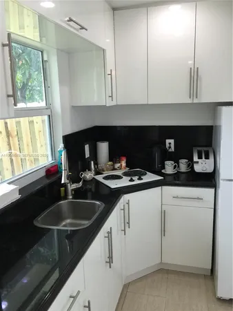 a kitchen with granite countertop a sink white cabinets and a stove