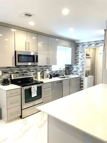 a kitchen with stainless steel appliances a stove a sink a microwave a center island and cabinets