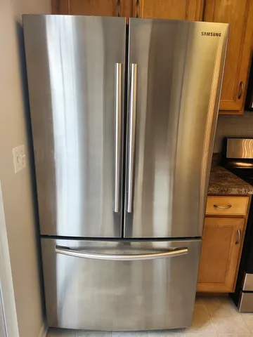 a kitchen with stainless steel appliances a refrigerator a stove a sink a center island and a refrigerator