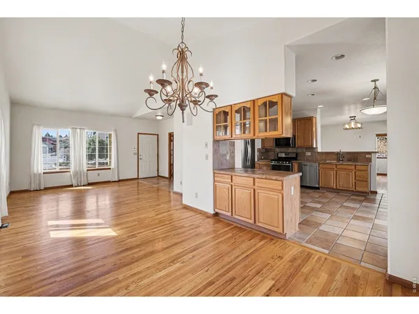 a open kitchen with stainless steel appliances granite countertop a stove top oven a sink dishwasher and white cabinets with wooden floor