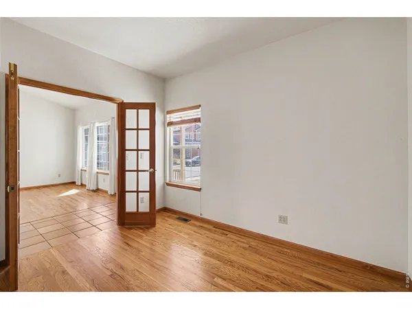 an empty room with wooden floor and windows