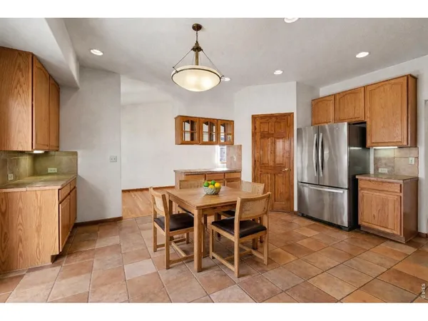 a kitchen with stainless steel appliances a refrigerator a stove a sink a dining table and chairs