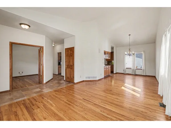 a view of an empty room with window and wooden floor