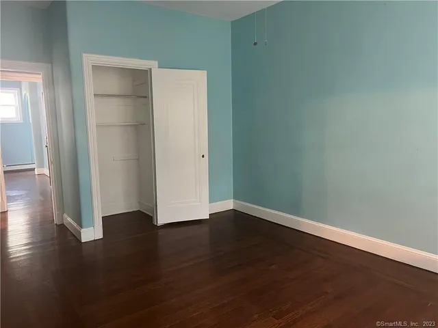 an empty room with wooden floor & closet and windows