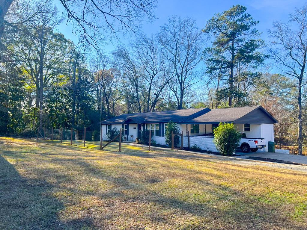 a view of a house with a big yard and large trees