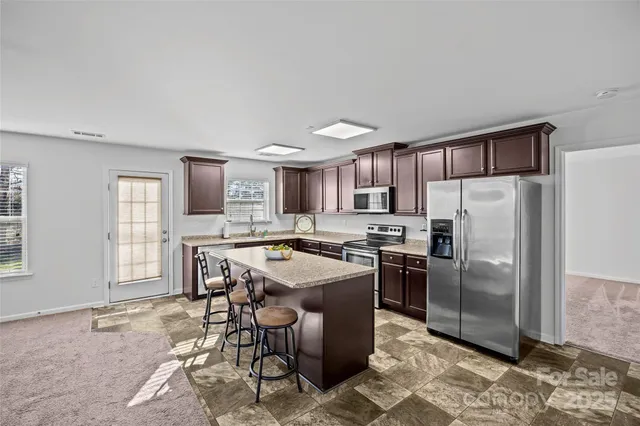 a kitchen with stainless steel appliances granite countertop a stove top oven a sink a dining table and chairs