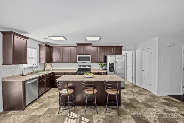 a kitchen with stainless steel appliances kitchen island granite countertop a sink and cabinets