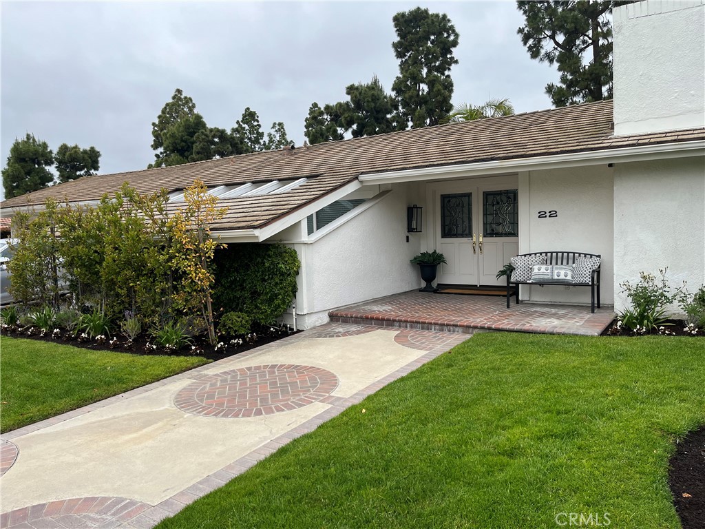 a view of a white house with a big yard and potted plants