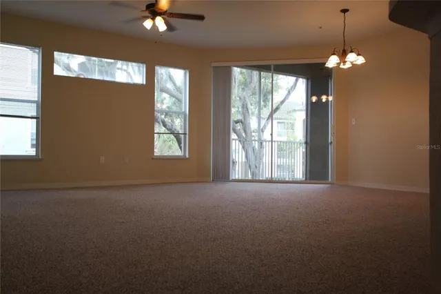 a view of an empty room with a chandelier fan and wooden floor