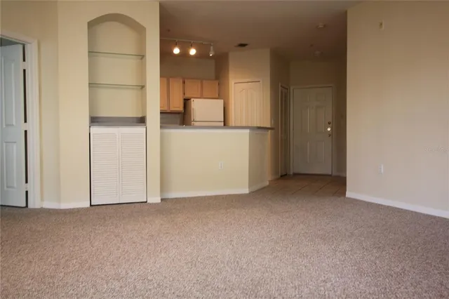 a view of an empty room and kitchen