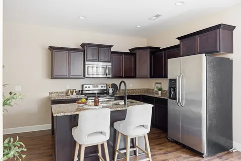 a kitchen with stainless steel appliances a table chairs refrigerator and microwave