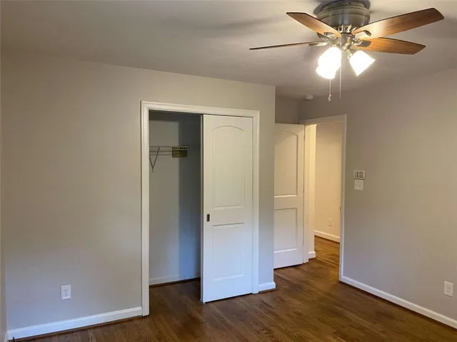 an empty room with wooden floor and a ceiling fan